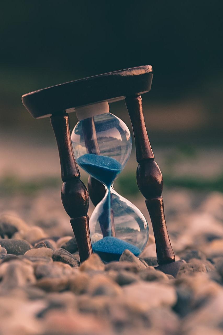 selective focus photo of brown and blue hourglass on stones